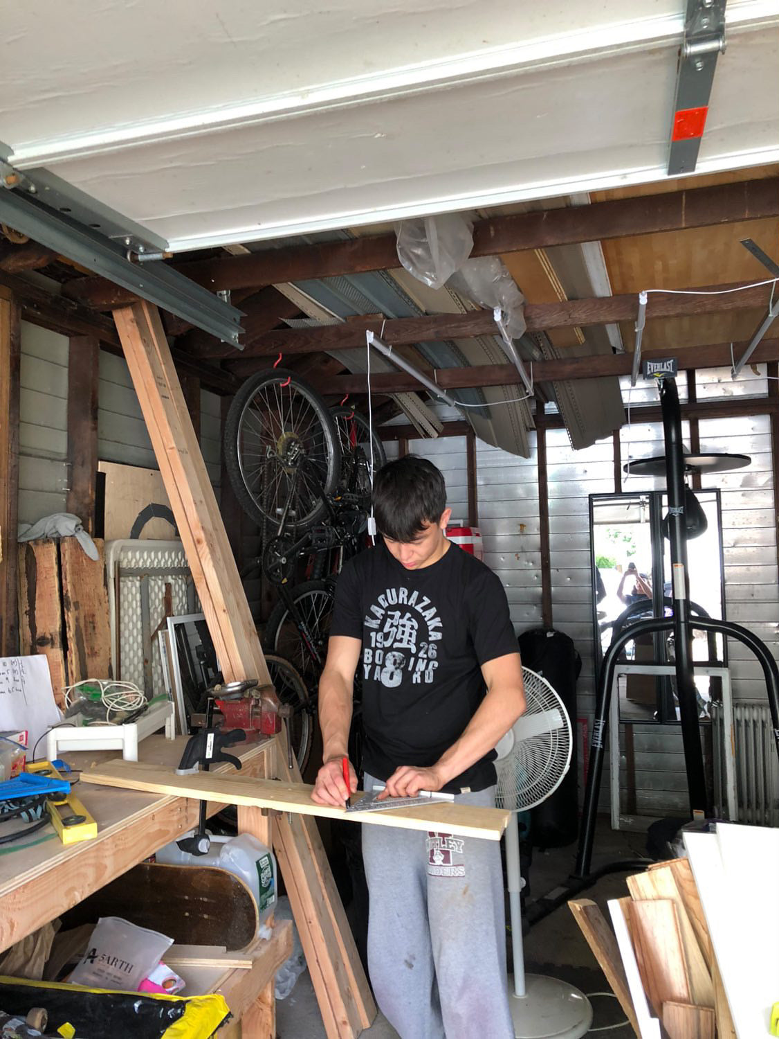 Bayshore Rings founder measuring and marking skateboard wood in his first garage workshop in Tampa, FL